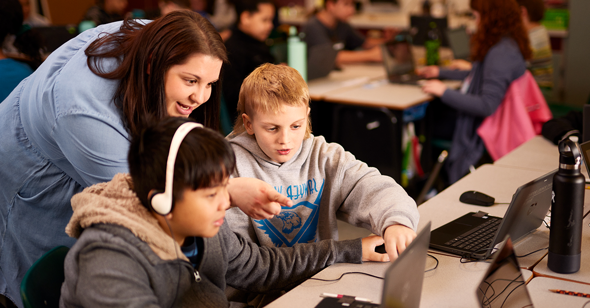 صورة لمعلم يساعد اثنين من الطلاب الشباب المشاركين في التعلم القائم على اللعبة.