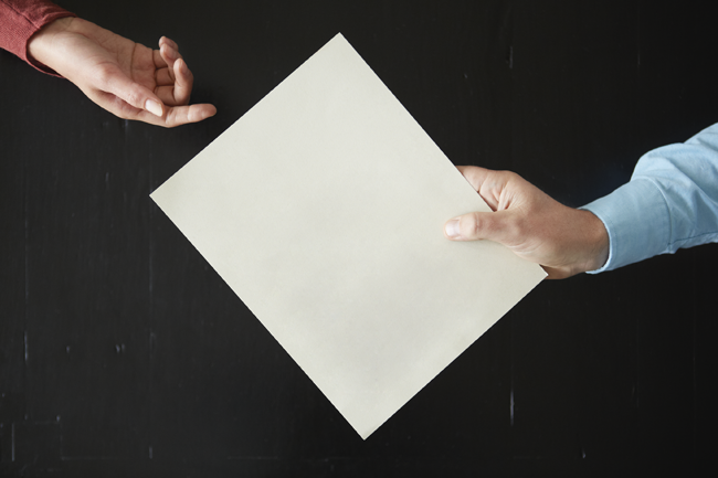 Screenshot of person handing a form to another person.