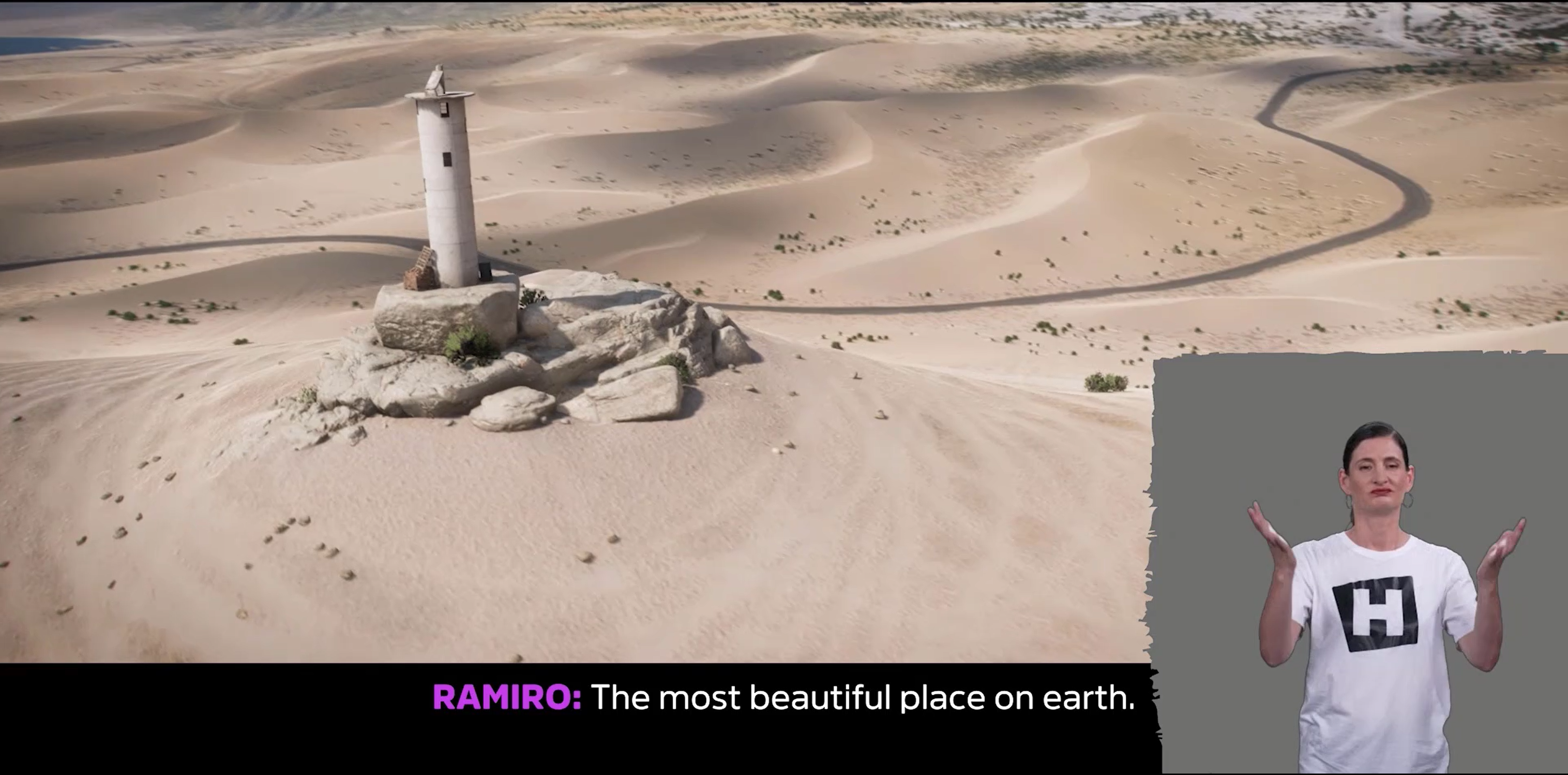 Screenshot von Forza Horizon 5 zeigt eine Wüstenlandschaft mit einer einzigen, sich windenden Straße, die durchführt. In der unteren rechten Ecke des Bildschirms ist eine Überlagerung mit einem Gebärdensprachdolmetscher zu sehen. Untertitel am unteren Bildschirmrand, zentriert: 