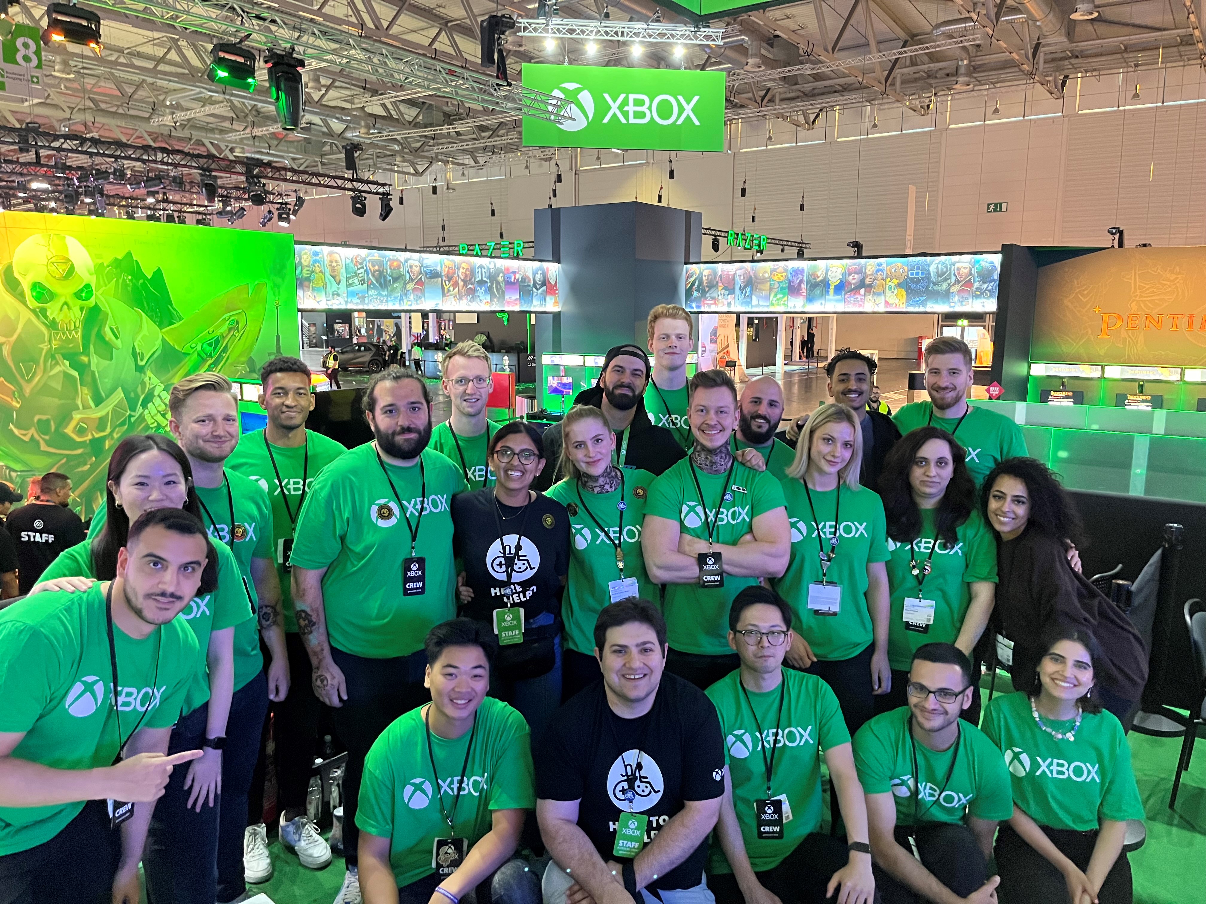 A large group of individuals wearing green and black Xbox shirts stand in an Xbox booth."