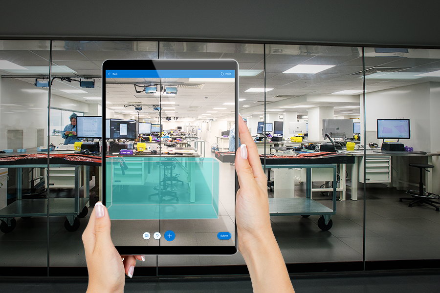 Ein Foto eines Tablet-Bildschirms, das einen digitalen Würfel zeigt, der über die Ansicht des Benutzers eines Büros gelegt wird.