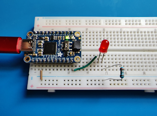 A picture of a breadboard with an FT232H adapter, a resister, an LED, and connecting wires.