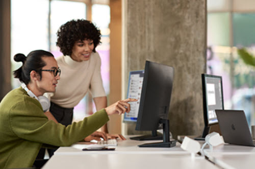 Photograph of two people working in an office who are looking at a computer screen.