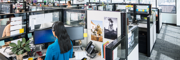 A photograph of a worker sitting in a large office talking on the phone.