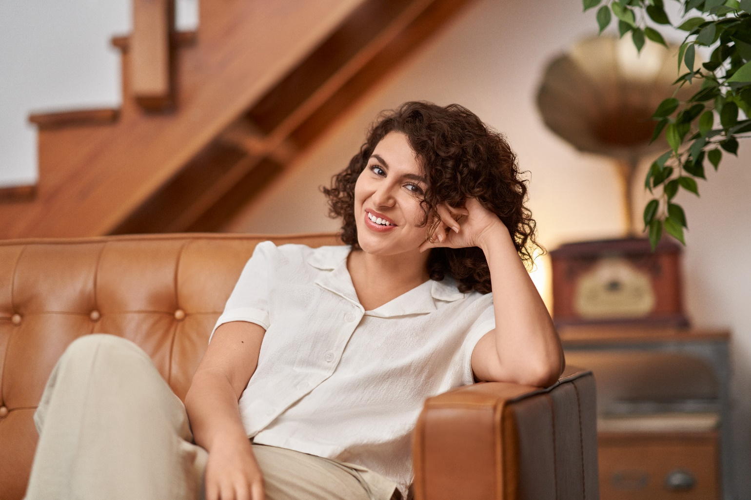 A photograph of a woman smiling sitting on couch.