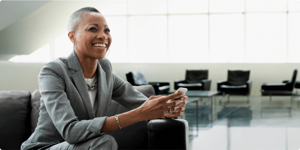 A woman in a suit smiling in an office lounge.