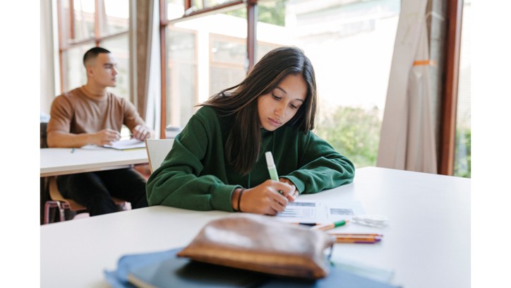 Student seated at a table writing on a worksheet