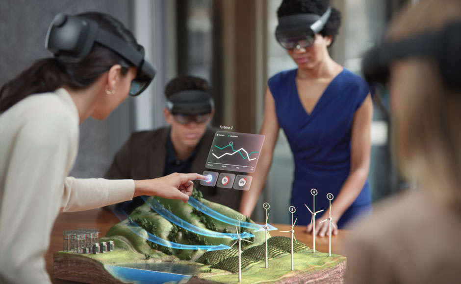 Photograph of multiple users wearing HoloLens headsets and standing around a holographic display and interactive menu on a tabletop.