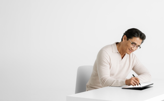 A photograph of a business professional using the Surface Slim Pen 2 on a Surface device at a desk.
