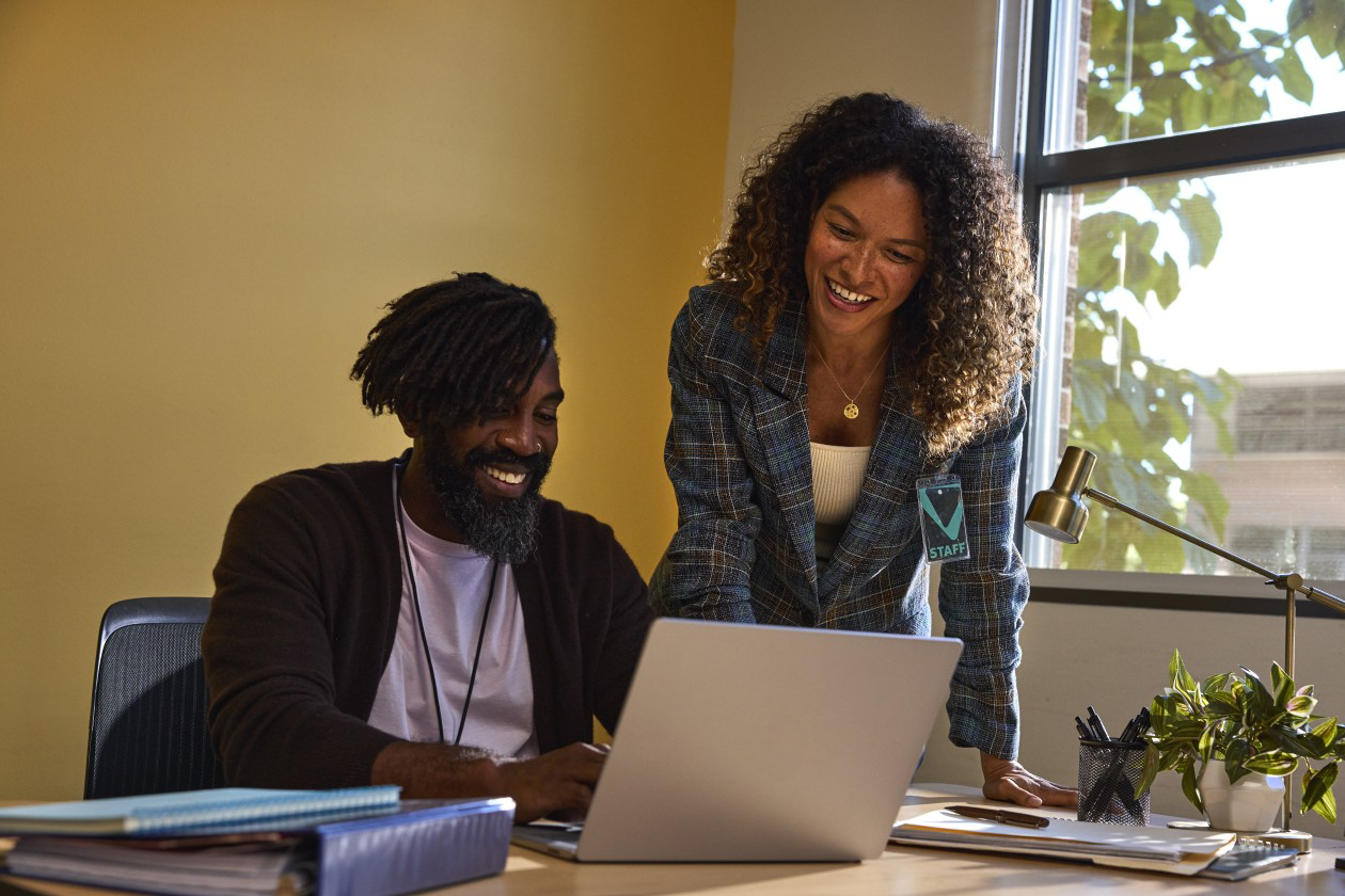 A photograph of educators working together using a laptop as part of a modern digital learning workflow.