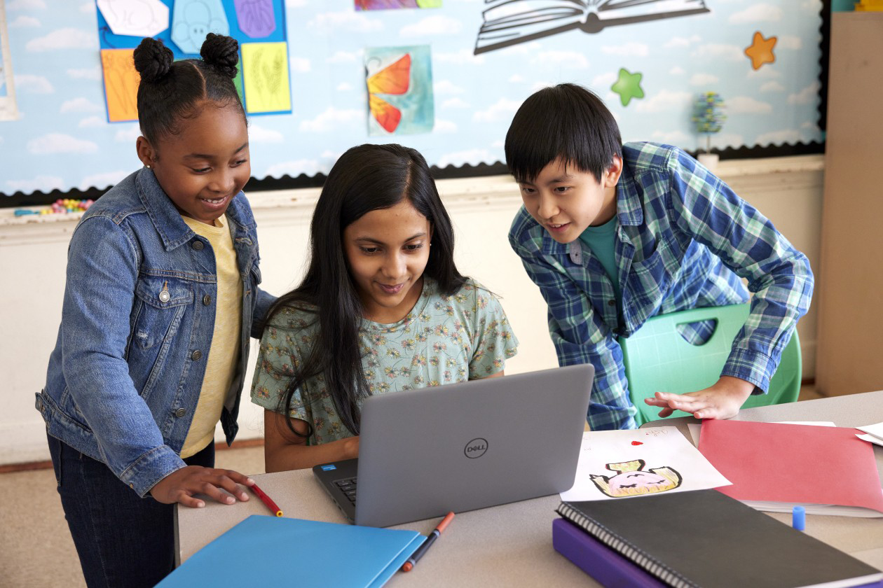 A photograph of a group of learners working together around a laptop during a collaborative digital learning activity.