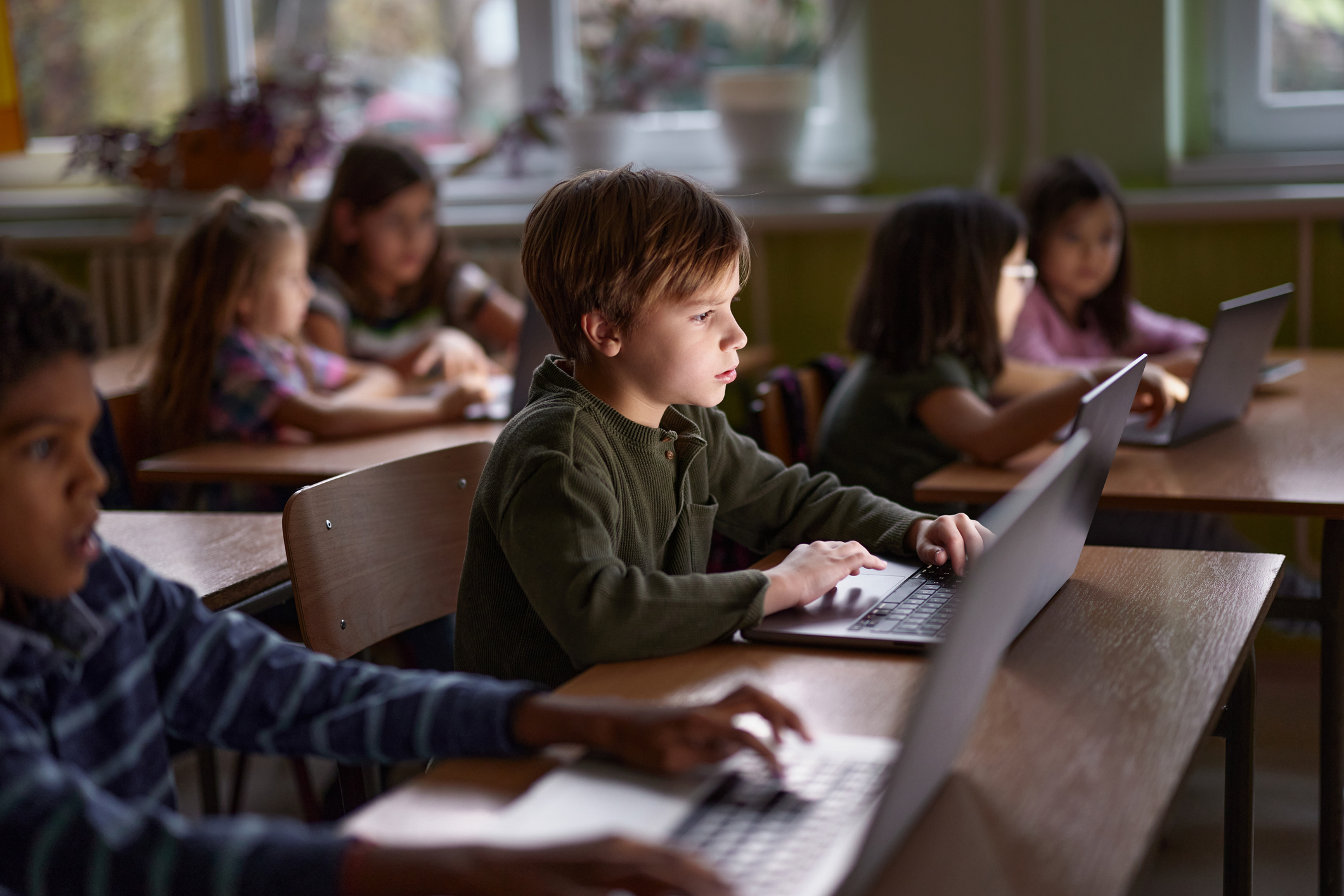 A photograph of students using laptops in a classroom to participate in a technology-supported learning environment.