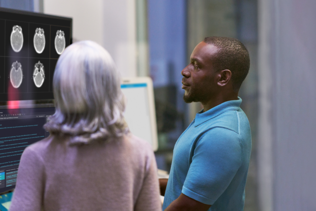 A photograph of an Azure developer and healthcare researcher collaborating near medical equipment in a clinical setting.