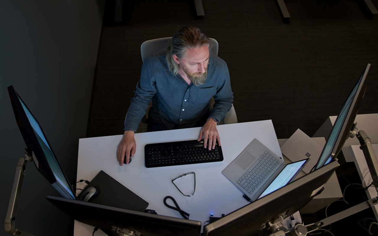 Photograph of a developer working at a desk with multiple monitors.