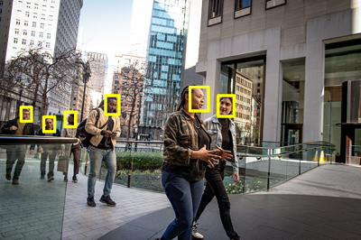 An image of multiple people on a city street with their faces highlighted.