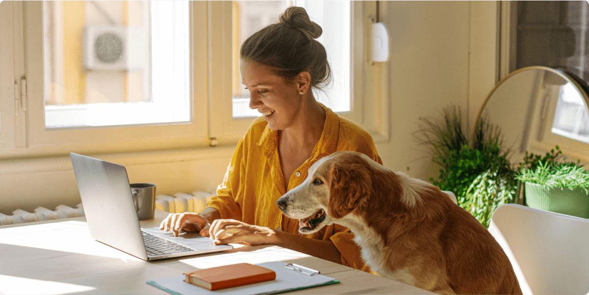 Una mujer trabajando en el portátil junto a su perro.