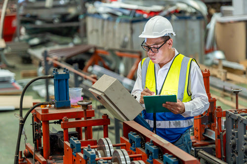 Fotografía en la que se muestra a los trabajadores en una planta de fabricación mirando datos.