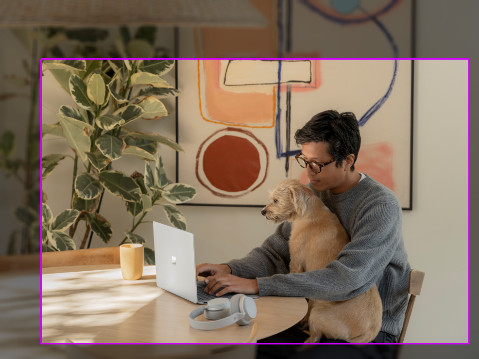 Photo of a man with a dog at a table. A 1.50 ratio bounding box is drawn.