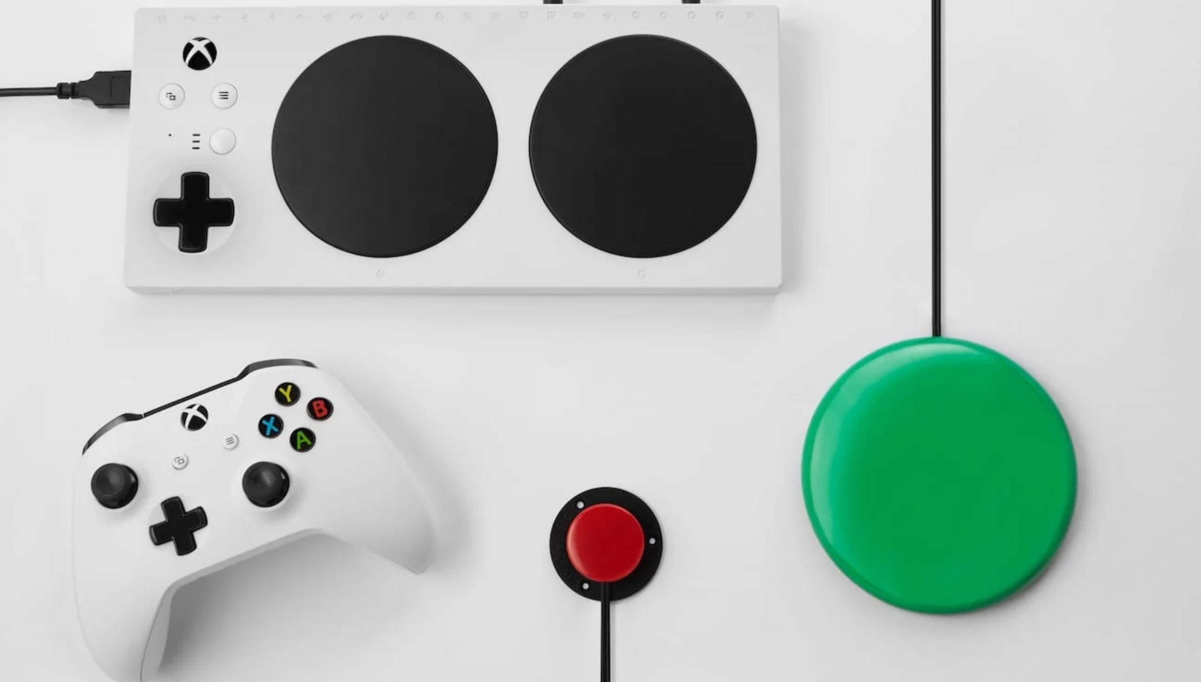 A collection of controllers including the Xbox Adaptive Control, a small red switch, a large green switch, and a standard Xbox Controller.