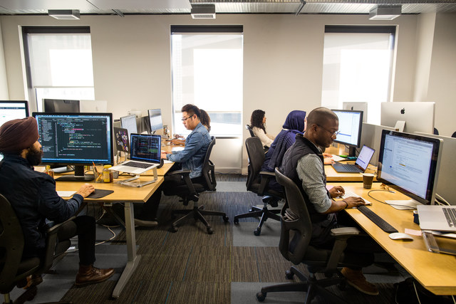 Photographie des employés d’entreprise travaillant sur des PC dans un espace de bureau.