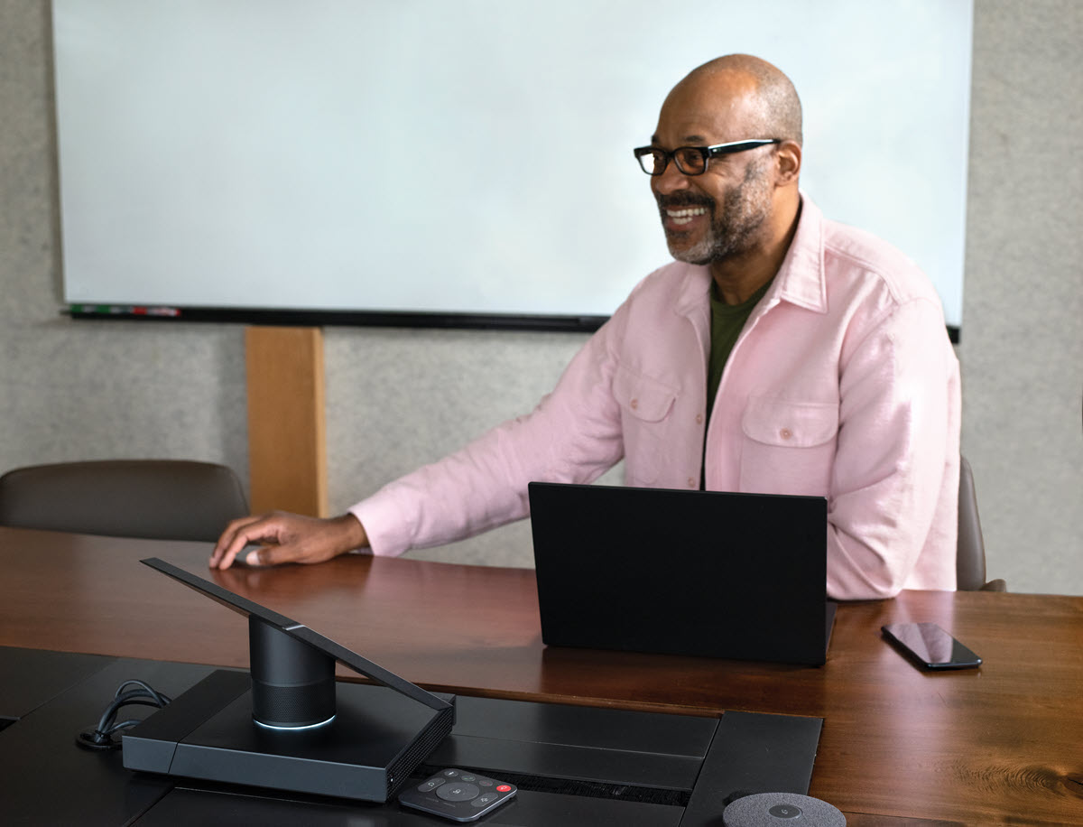 Photo of a presenter at a laptop in front of a screen.