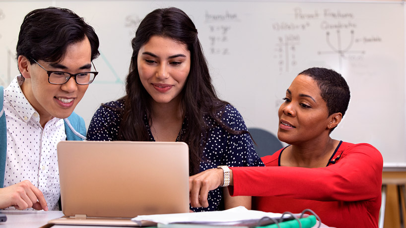 Photograph of three educators working together on a computer.