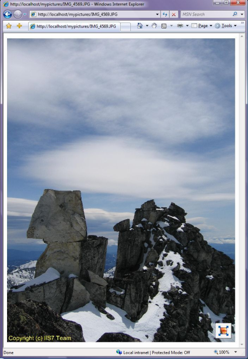 Screenshot of the web page displaying an image of snow covered rocky mountains on the backdrop of a cloudy sky.