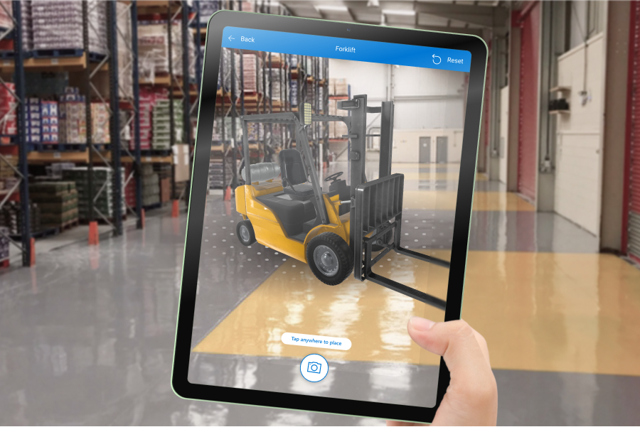 Foto dello schermo di un tablet che mostra un modello 3D di un carrello elevatore sovrapposto a una vista interna del magazzino.