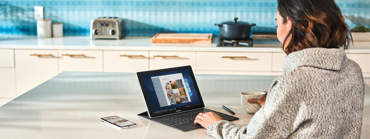 キッチンで Microsoft Surface デバイスを使用している女性の写真。