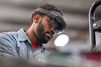 Photo of a HoloLens auto worker using Dynamics 365 guides for his hands-on training.