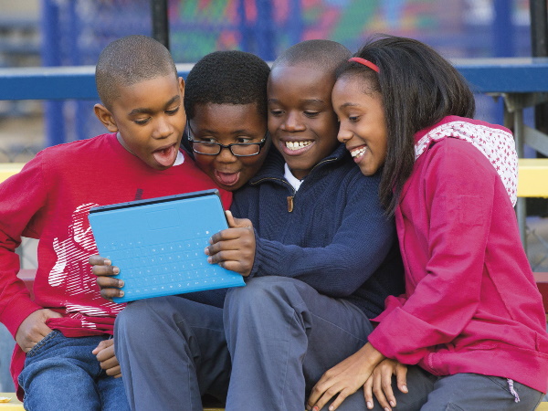 태블릿 컴퓨터 주위에 모인 학생들의 사진.