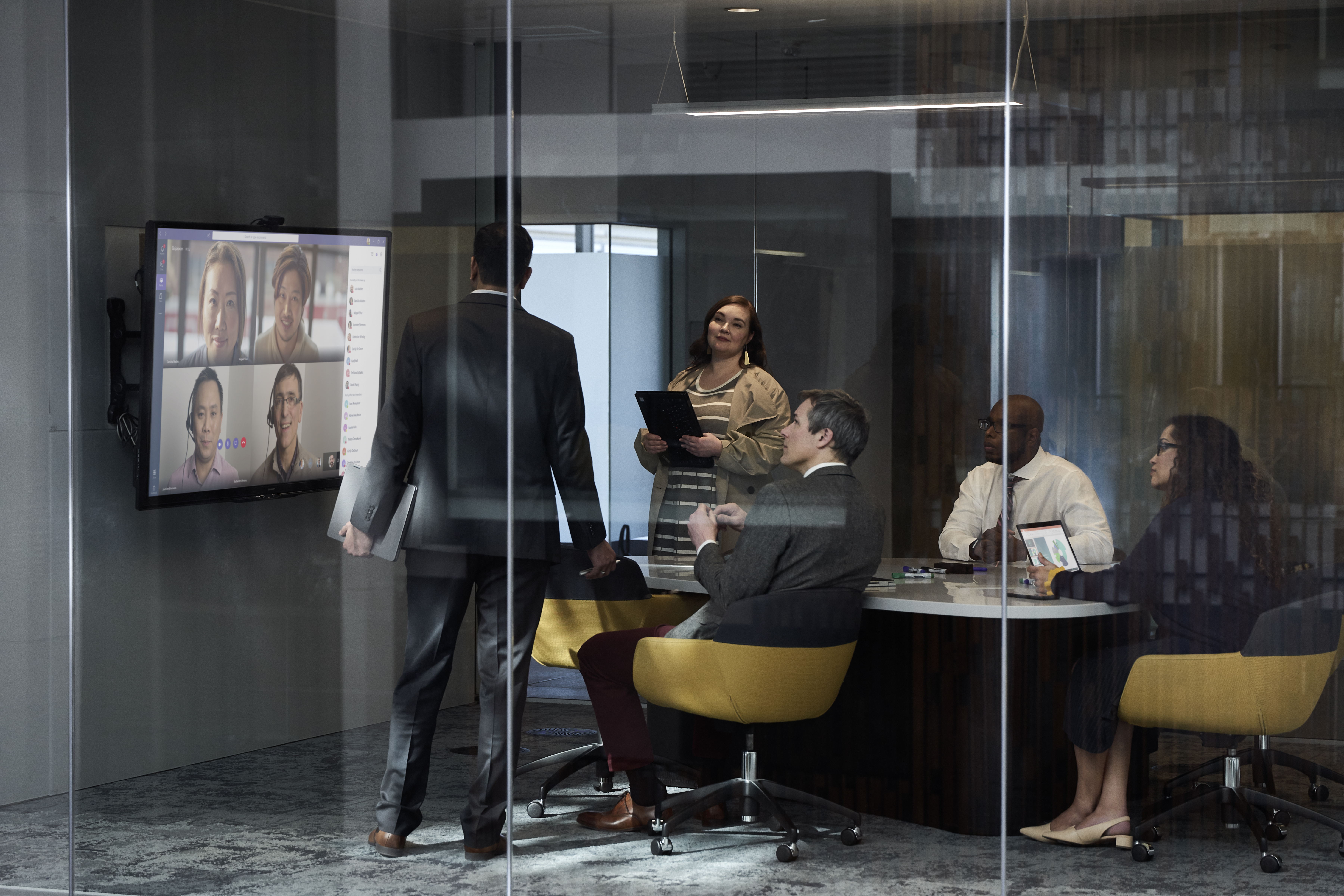 Een groep kantoormedewerkers in een vergadering bespreekt afbeeldingen op een groot scherm.
