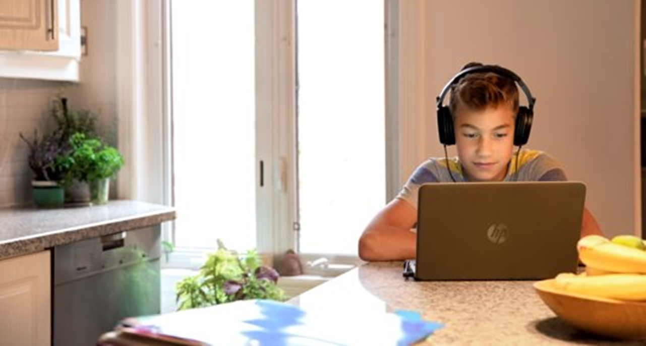 Imagem de um estudante a trabalhar com um PC pessoal e headset.