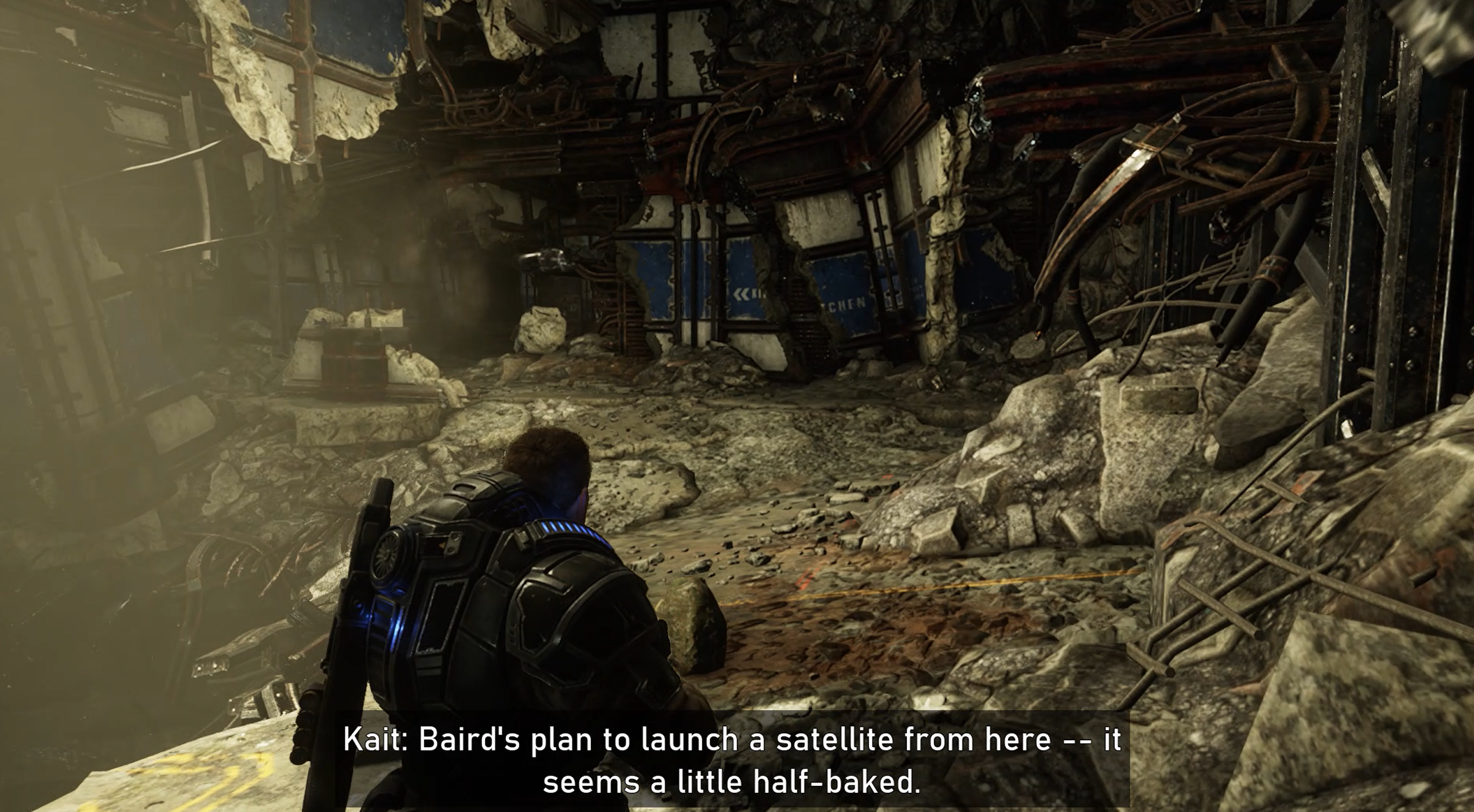 Subtitle with large text over a semi-opaque background during active gameplay in Gears 5 that reads, "Kait: Baird's plan to launch a satellite from here -- it seems a little half-baked."