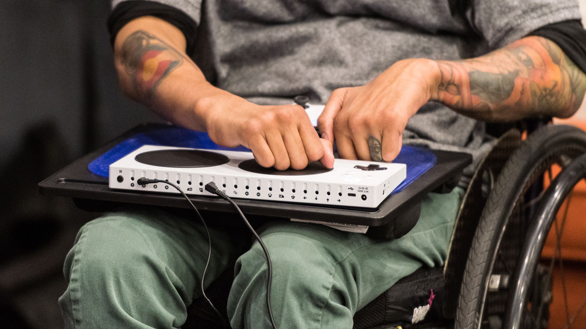 Uma imagem de um jogador em uma cadeira de rodas usando um Controlador Adaptável xbox em uma placa de volta.