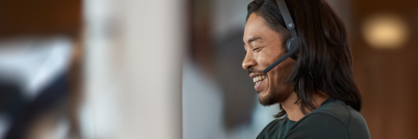 A photograph of a customer rep talking on the phone through a headset.