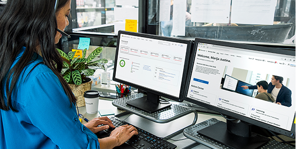 Microsoft Services Hub'da iki monitörlü bir bilgisayarda çalışan kişi.