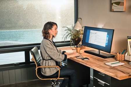 一个女人坐在办公桌前使用电脑工作的图片。