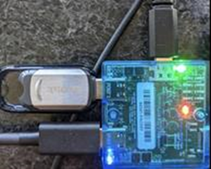 Microsoft USB 測試控管的圖片 (MUTT) 裝置，且藍色 LED 已亮起。